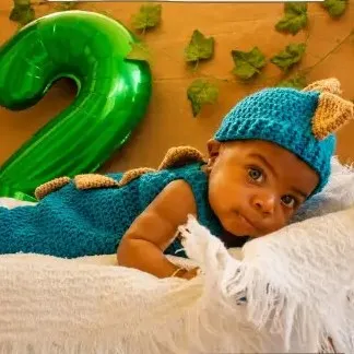 Bebé modelando una pieza tejida por AMV Crochet