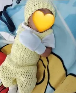Bebé modelando una pieza tejida por AMV Crochet