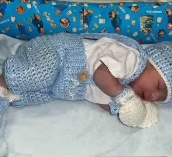 Bebé modelando una pieza tejida por AMV Crochet
