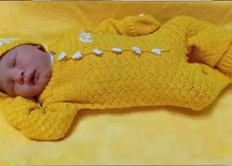 Bebé modelando una pieza tejida por AMV Crochet