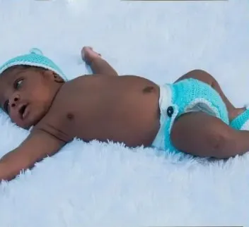 Bebé modelando una pieza tejida por AMV Crochet