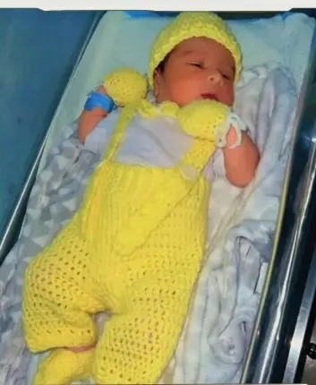 Bebé modelando una pieza tejida por AMV Crochet